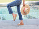 Woman wearing Pelican leather slide sandals in gold/honey with jeans by the pool