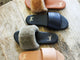 Group shot of Baza leather slides in honey and black with Baza Shearling slide sandal in bronze/black and honey/tan.