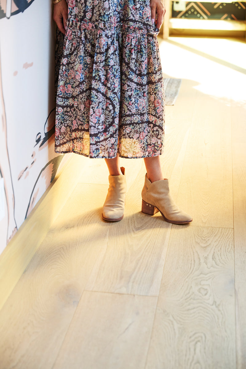 Woman wearing Eagle suede heeled boot in stone with floral dress