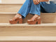 Woman wearing Emu leather platform heel sandal in tan with jeans on steps