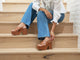 Woman wearing Emu leather platform heel sandal in tan with jeans on steps