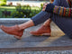 Woman wearing Falcon leather booties in cognac with jeans and sweater.