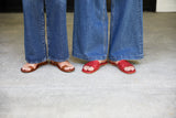Women wearing Finch leather toe ring sandals in tan and Honeybird leather slide sandals in red with jeans