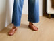 Woman wearing Gallito leather slide sandals in tan with jeans.