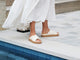 Woman wearing Hen leather platform criss-cross sandals in eggshell with white dress