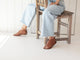 Woman wearing Loon leather ankle tie sandal in tan with jeans sitting on a chair