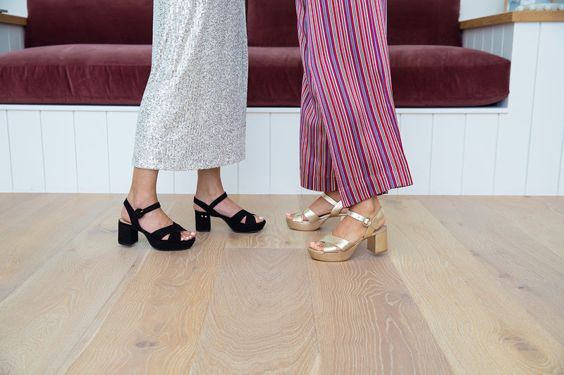 Women wearing Partybird platform heeled sandals in black and gold with party attire