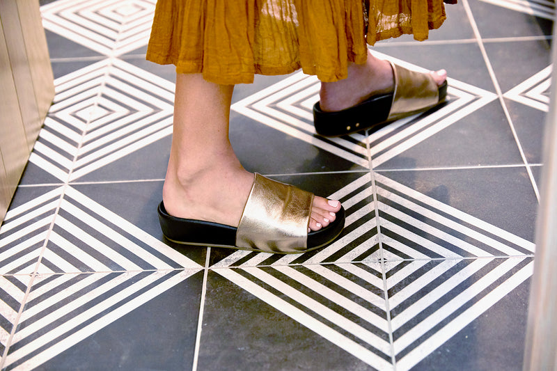 Woman wearing Pelican leather platform sandals in bronze/black with dress