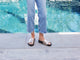 Woman wearing Pelican leather platform sandal in bronze/black with jeans by the pool