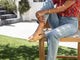 Woman wearing Pelican leather platform slide sandals in beach with jeans and floral top on a chair