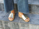 woman wearing Pelican leather slide sandals in platinum/beach with jeans on steps