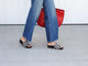 Woman wearing Pelican Woven leather platform sandals in eggshell/black with jeans carrying red woven bag