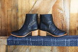 Pheasant leather boots in black/tan - side shot on bench