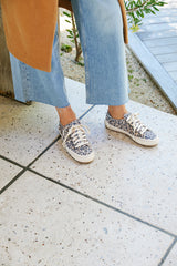 Woman wearing Sandpiper sneakers in leopard  with jeans and coat