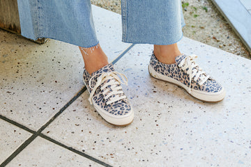 Woman wearing Sandpiper sneakers in leopard  with jeans and coat