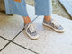 Woman wearing Sandpiper sneakers in leopard  with jeans and coat