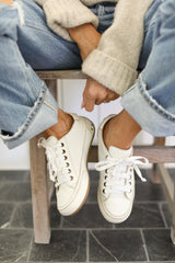 Woman wearing Sandpiper leather sneakers in white with jeans and sweater