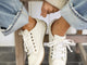 Woman wearing Sandpiper leather sneakers in white with jeans and sweater