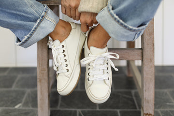 Woman wearing Sandpiper leather sneakers in white with jeans and sweater