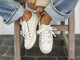 Woman wearing Sandpiper leather sneakers in white with jeans and sweater