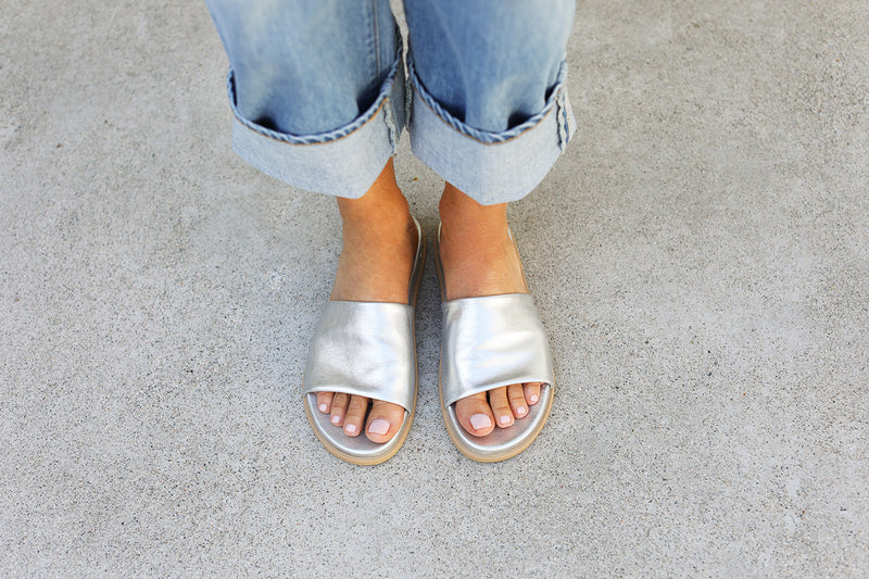 Woman wearing Starling leather slide sandal in silver with cuffed jeans