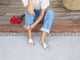 Woman wearing Starling leather slide sandal in silver with cuffed jeans on a step