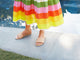 Woman wearing Sugarbird leather slide sandals in beach with colorful striped dress