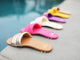 Group shot of Sugarbird slide sandals in gold/honey, azalea, eggshell, iris, sunflower, and beach.