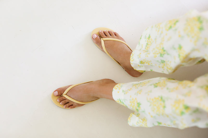 Woman wearing Sunbeam leather flip flop sandals in glow with floral pants