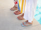 Women wearing Sunbeam leather flip flop sandal in sky, beach, lipstick, and bronze