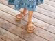 Woman wearing Warbler leather slide sandal in tan with patterned dress